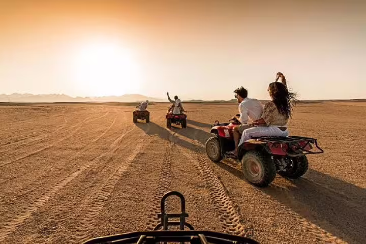 ATV quad bike convoy in Hurghada desert at golden hour, thrilling safari adventure tour with camel ride add-on