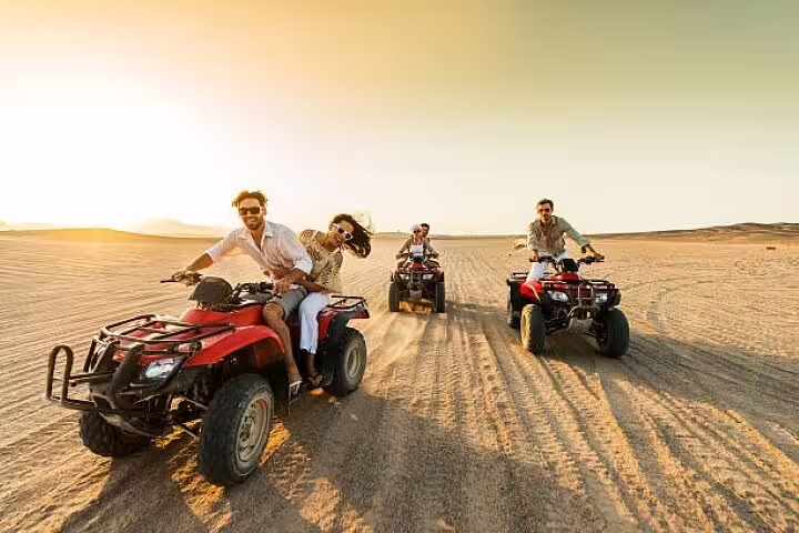 Riders driving ATVs across sandy dunes at sunset on Double quad bike safari tour from Sharm El Sheikh