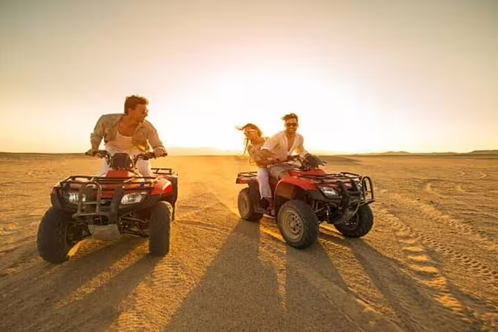 Couple riding ATV quad bikes at sunset in Marsa Alam desert, part of Bedouin dinner and show tour