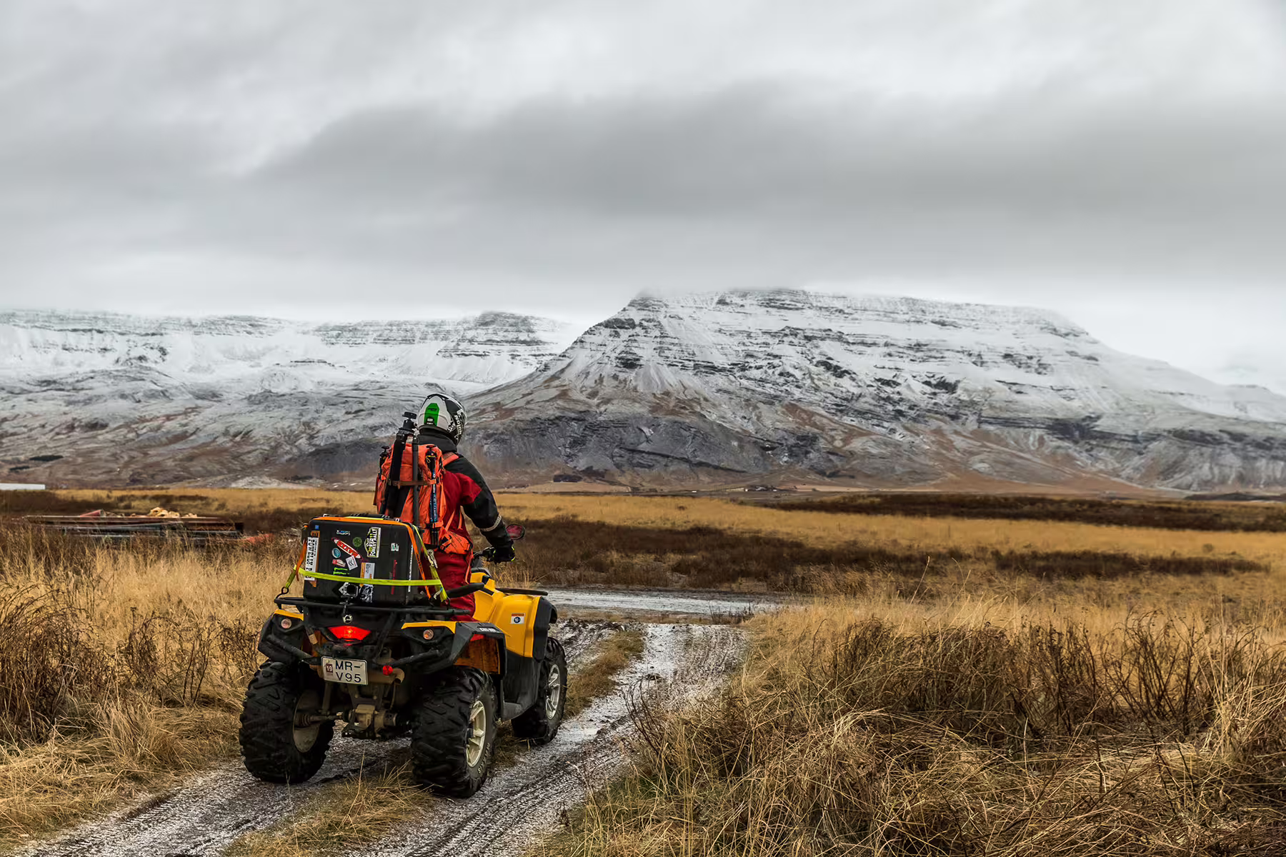 ATV rider explores rugged volcanic landscape with snow-capped mountains during 3-hour adventure tour in Icelandic springs.