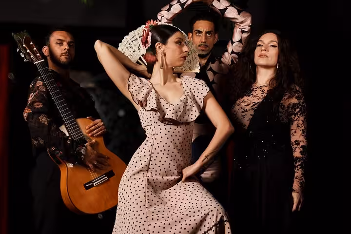 Passionate flamenco performers in vibrant costumes with a guitarist at an authentic live show in Barcelona.