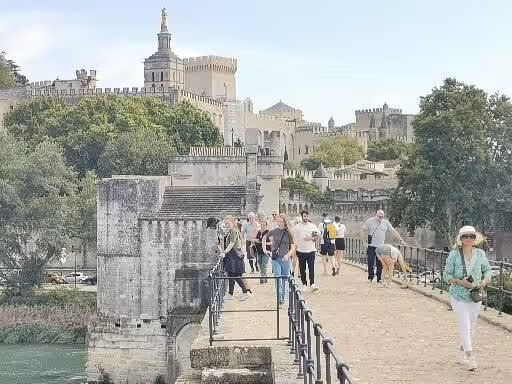 Walkers on Pont Saint-Bénézet with Avignon Papal Palace, Provence Christian heritage tour France