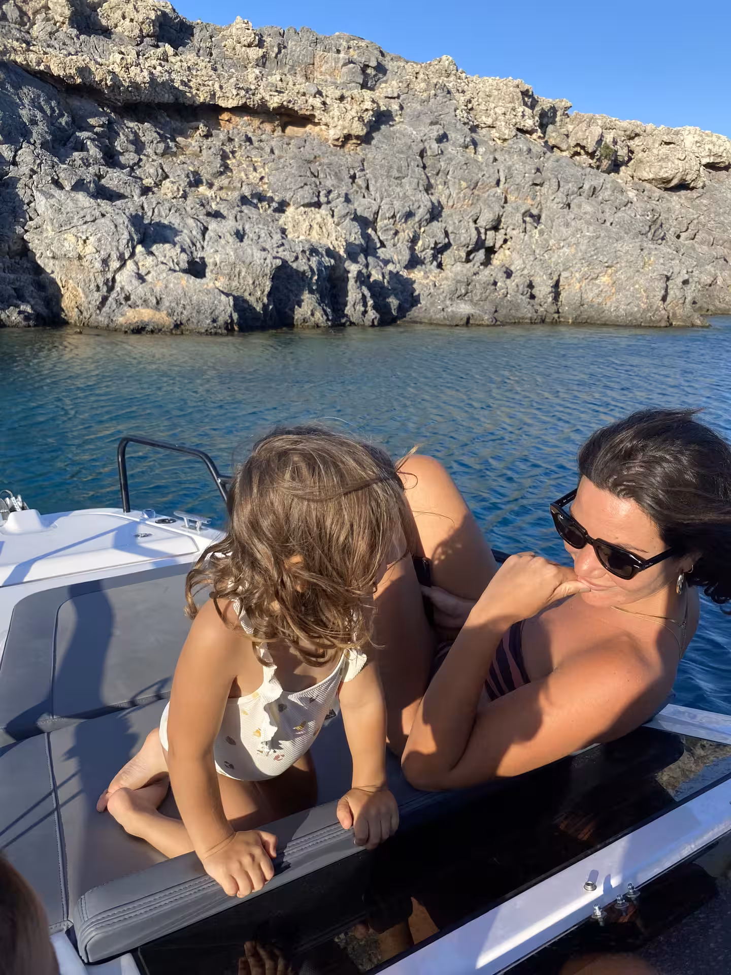 Family relaxing on Axopar 25 CT boat by Lindos rocky cove, Rhodes, during Discover Gems of Lindos tour