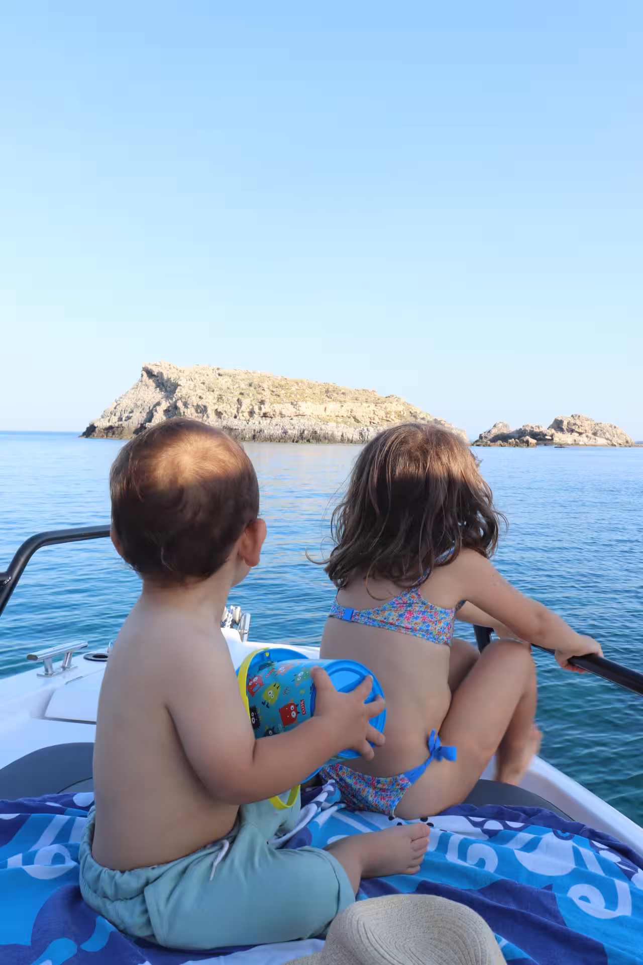 Kids relaxing on the bow during an Axopar 25 CT full-day boat rental, cruising to rocky island coves