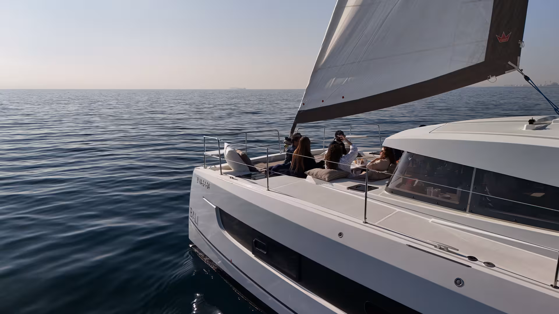 Friends relaxing on deck of Bali 4.2 sailing catamaran on a 2-hour private luxury cruise from Barcelona
