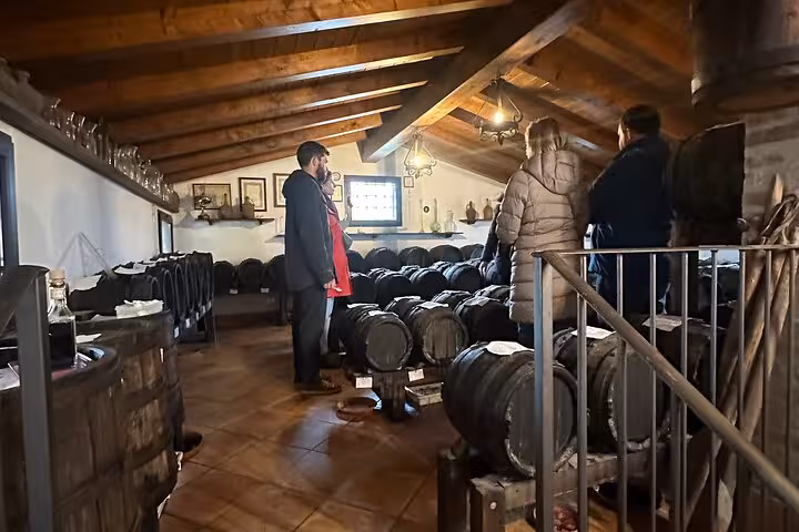 Visitors exploring a balsamic vinegar cellar filled with barrels during the Taste Tour in an Italian attic.