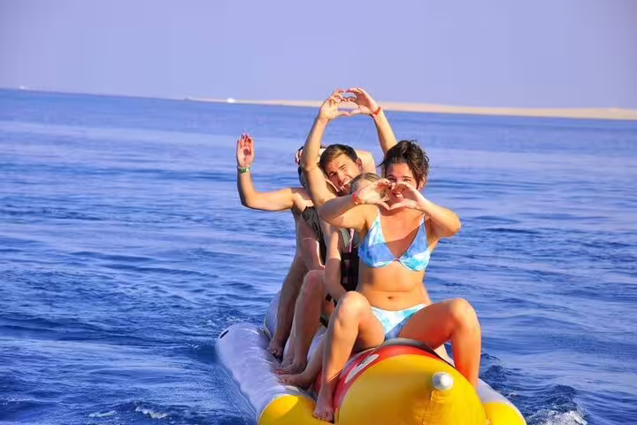 Guests riding a banana boat on the Red Sea during Dolphin House VIP boat snorkeling day trip from Hurghada
