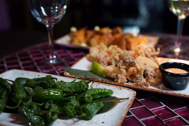 A delicious spread of traditional Spanish tapas including padrón peppers and calamari, served at a Barcelona flamenco show.