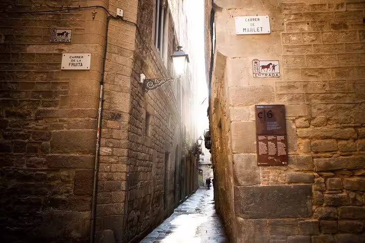 Narrow historic alleyway in the Jewish Quarter of Barcelona, showcasing stone walls and atmospheric lighting for a cultural tour.