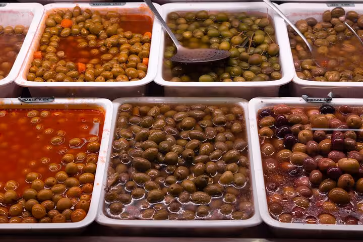 Marinated olives in market trays, tasting stop on Barcelona private small group food tour in La Boqueria