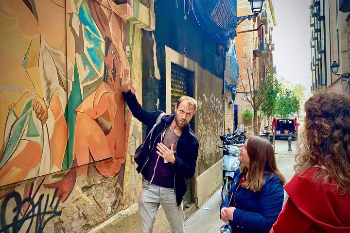 Tour guide explains vibrant street art to visitors in Barcelona's Old Town, highlighting cultural and artistic heritage.