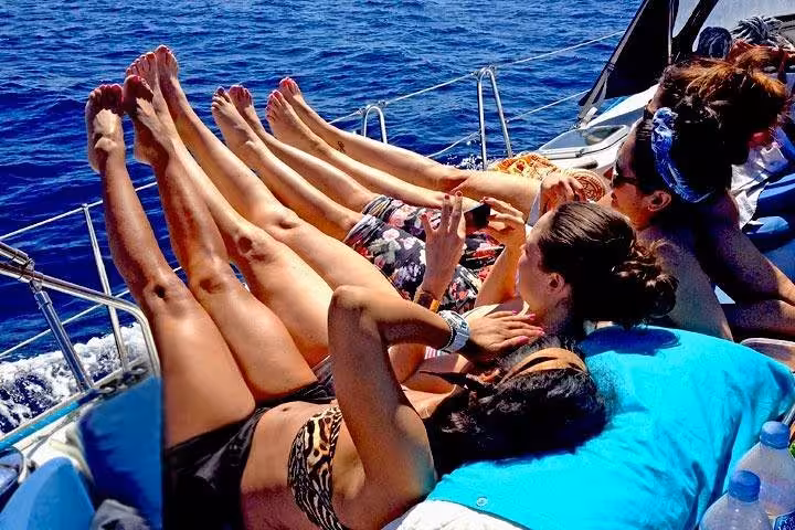 Guests sunbathing on a private Barcelona sailboat cruise with open bar and snacks on the Mediterranean