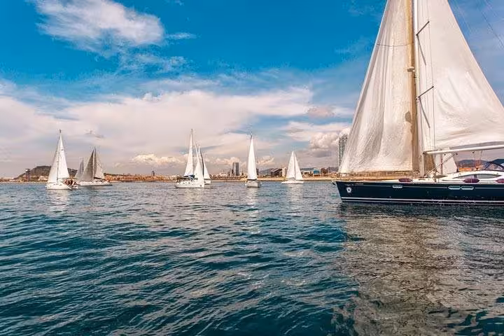 Private sailing in Barcelona with open bar and snacks, cruising past sailboats on the Mediterranean Sea