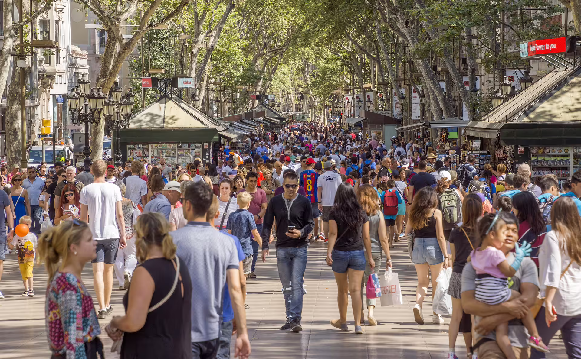 Crowds strolling under plane trees on La Rambla Barcelona, El Raval walking tour with multilingual audioguide