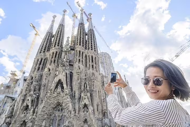 Tourist capturing the iconic Sagrada Familia in Barcelona, highlighting its intricate architecture on a sunny day.