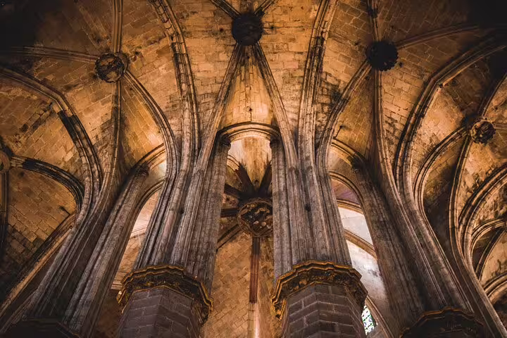 Gothic arches and columns of a historic cathedral in Barcelona, showcasing intricate architectural design.