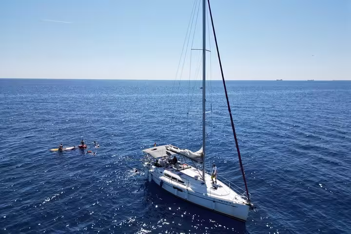 Sailboat gliding on the sparkling Mediterranean Sea near Barcelona, offering a small group sailing tour with snacks and cava.