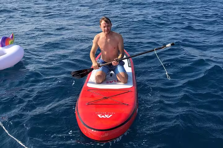Man enjoying paddleboarding on clear blue waters during a Barcelona small group sailing tour with snacks and cava.