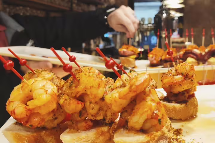 Close-up of flavorful shrimp tapas skewered with red sticks on a plate in a Barcelona eatery.