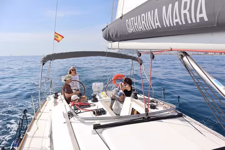 Small group enjoying sailing on a sunny day in Barcelona, relaxing with snacks and cava on a luxurious yacht with a Spanish flag.