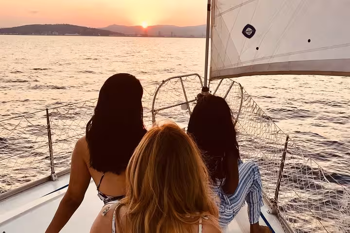 Guests relax on a sailboat at sunset in Barcelona, enjoying open bar and snacks on a sea tour