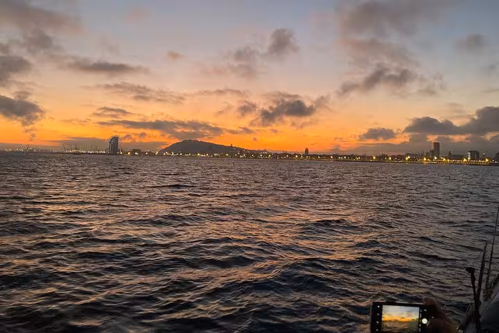 Barcelona coastline at dusk from the sea, sunset sailing tour view with open bar and snacks in Barcelona