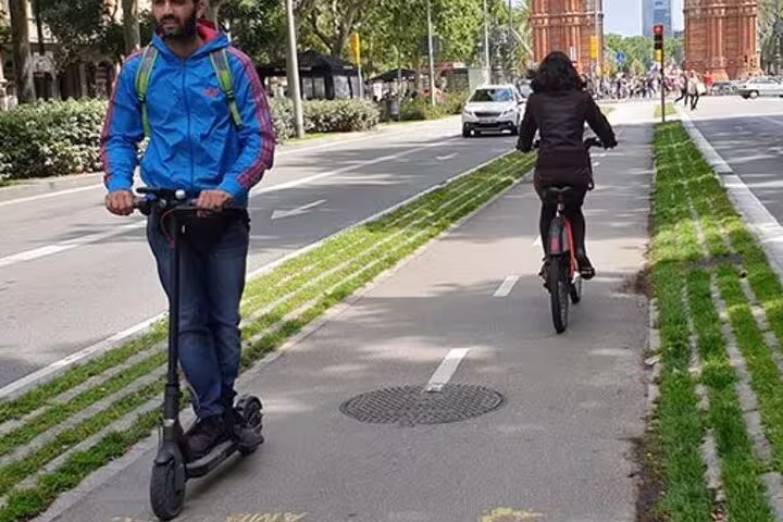 Cyclists and scooter riders on a dedicated lane in Barcelona, showcasing sustainable urban mobility initiatives.