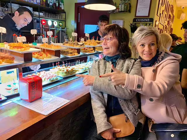 Two women enjoy a vibrant selection of tapas at a traditional Barcelona tavern during a food and drink private tour.