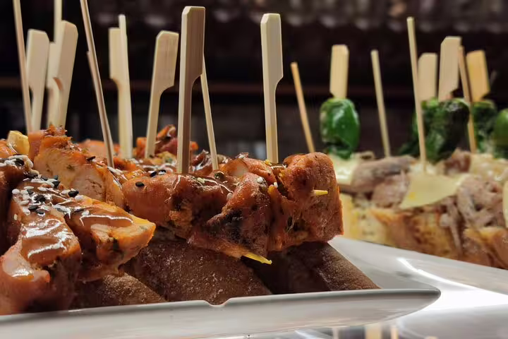 Assorted tapas with skewered meats and vegetables on rustic bread at a local eatery in Barcelona's wine tour.