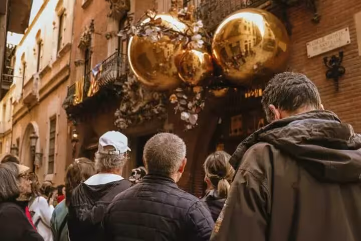 Tourists admire unique golden sculptures on historic street during Barcelona walking tour.