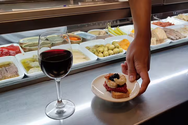 Glass of red wine and a gourmet tapa with caviar in a vibrant Barcelona tapas bar.