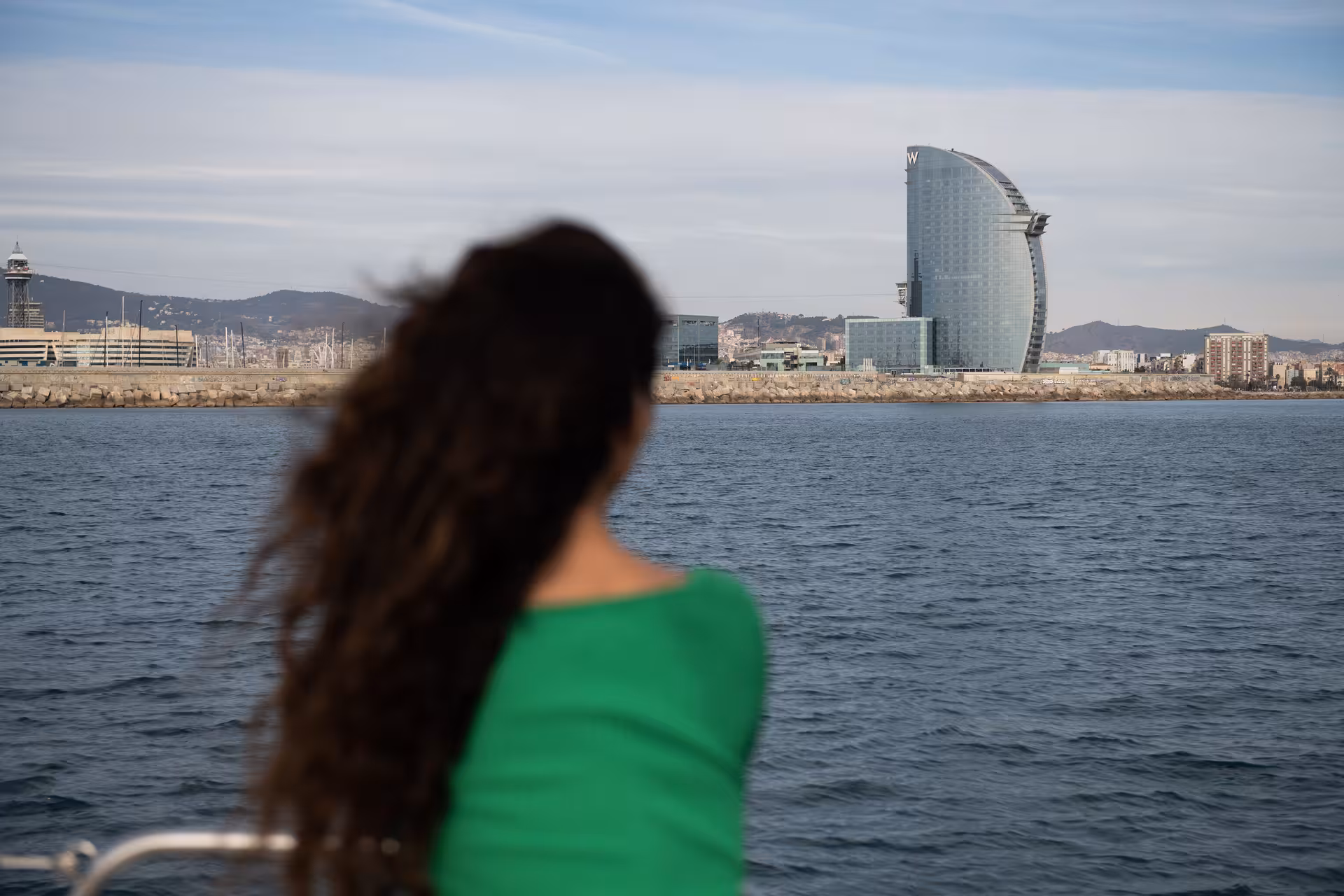 Woman on a Barcelona sailing yacht facing the W Hotel, scenic setting for a romantic marriage proposal tour