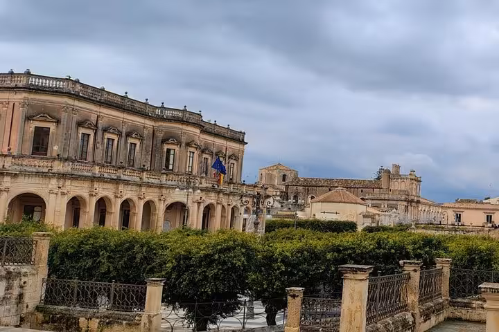 Elegant Baroque buildings in Noto, surrounded by lush greenery and historic charm, perfect for cultural exploration.