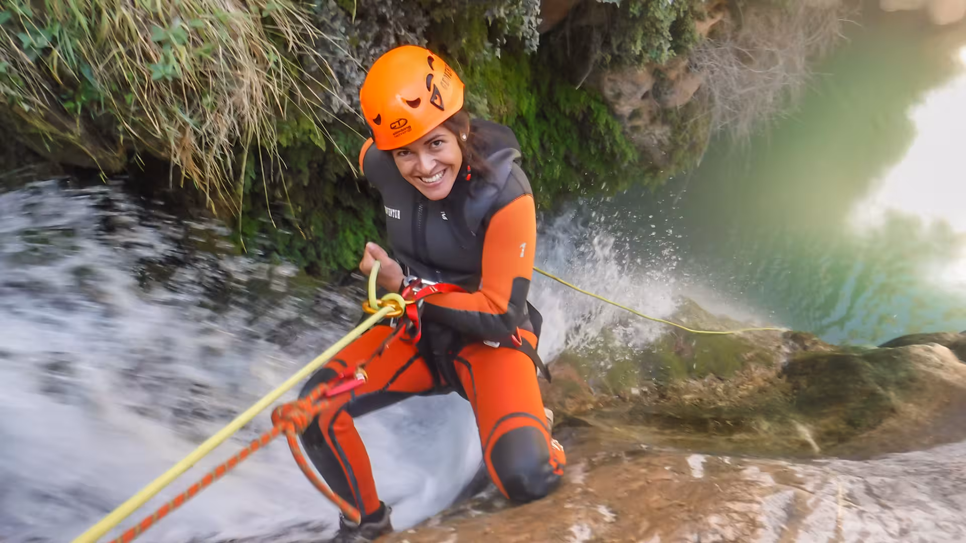 Participante en barranco acuático Utrillas, Teruel, rapelando con casco y neopreno sobre cascada