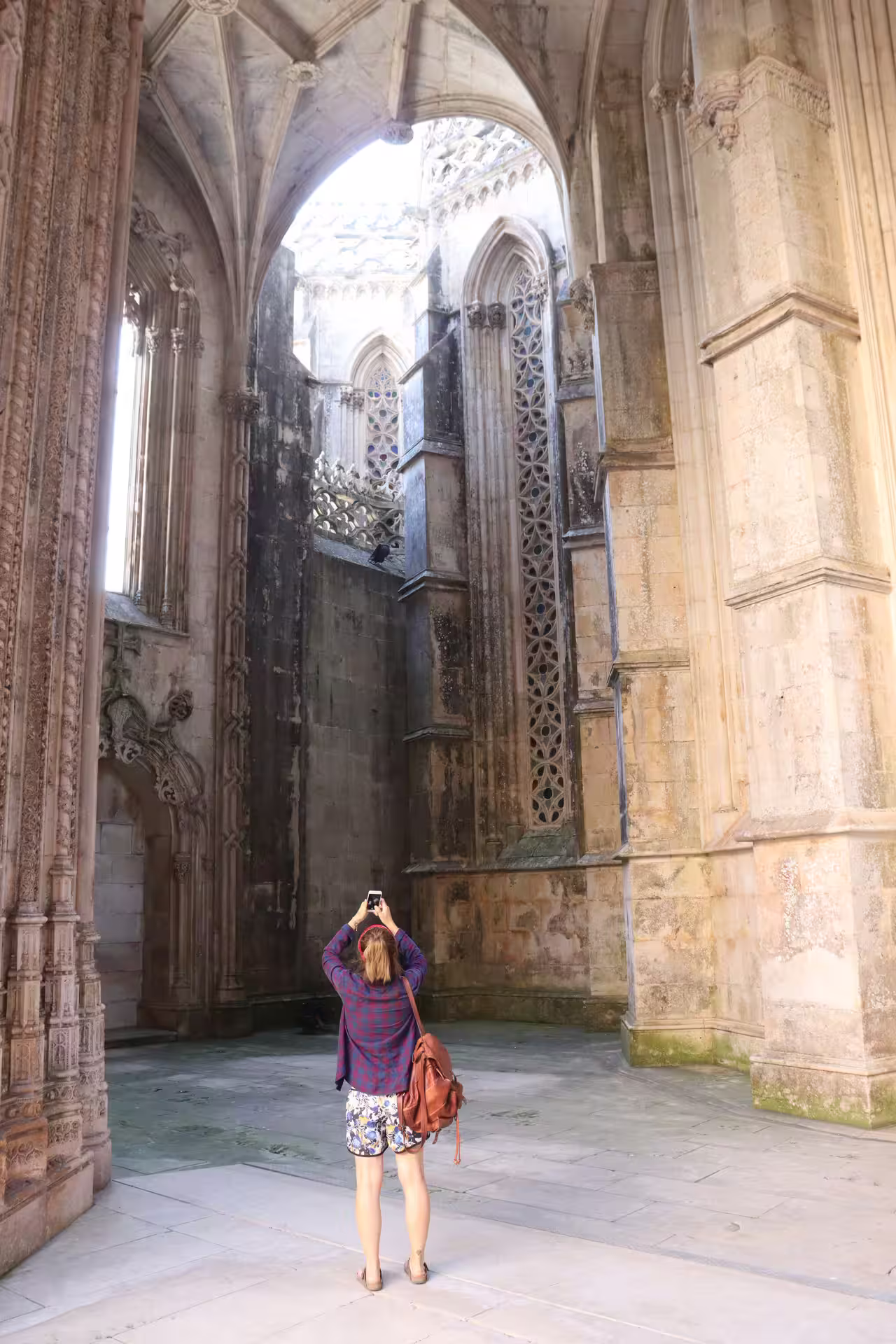 Visitor photographing intricate Gothic architecture at Batalha Monastery on a private tour through Tomar, Fátima, and Batalha.