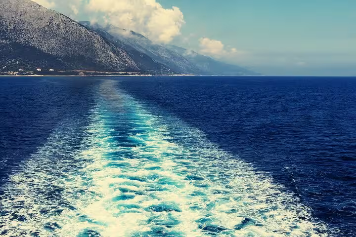Boat wake cutting through the Ionian Sea by rugged coastline on a locals BBQ boat trip in Greece