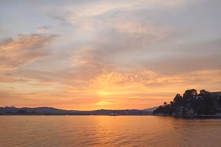 Golden sunset over the Ionian Sea on a local BBQ boat trip, calm waters and coastline views