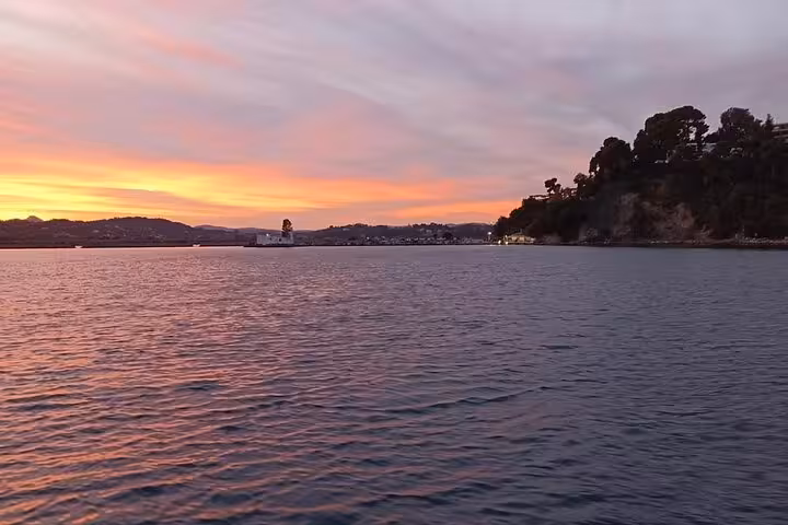 Sunset over the Ionian Sea near a wooded headland, captured on a locals BBQ boat trip with sea views