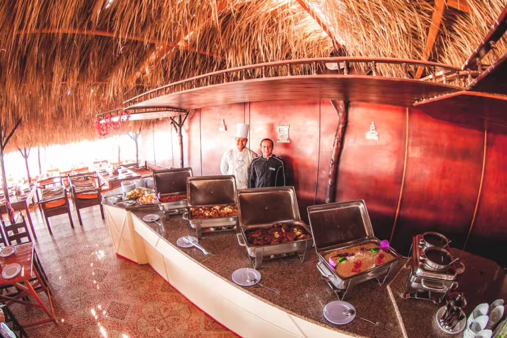 Open-air beach buffet under a thatched roof on Paradise Island day tour, with hot dishes and island lunch setup