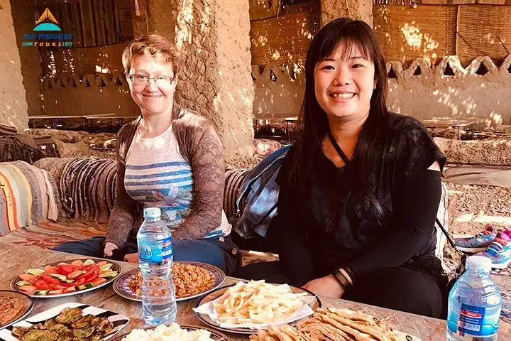 Tourists enjoying traditional Bedouin lunch in an oasis camp on 15-day Egypt tour to Pyramids Luxor Aswan Oasis