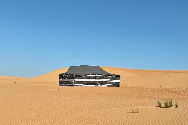 Traditional Bedouin tent in the vast Wahiba Sands desert, showcasing the serene beauty of Oman’s golden dunes.
