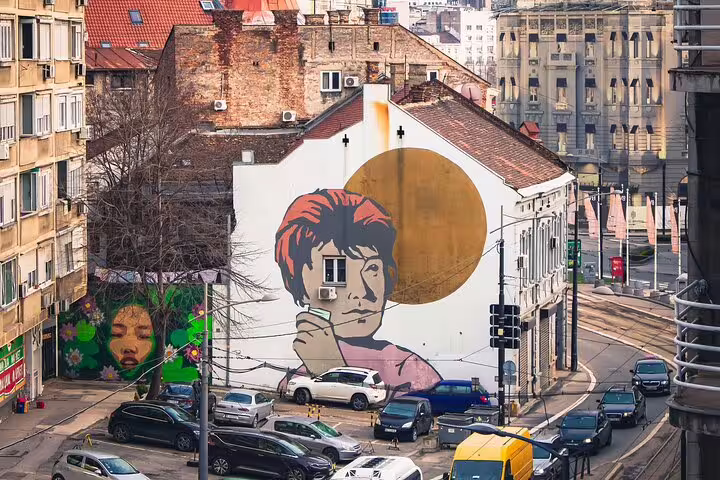 Large portrait mural with golden circle on Belgrade street, seen on private street art walking tour