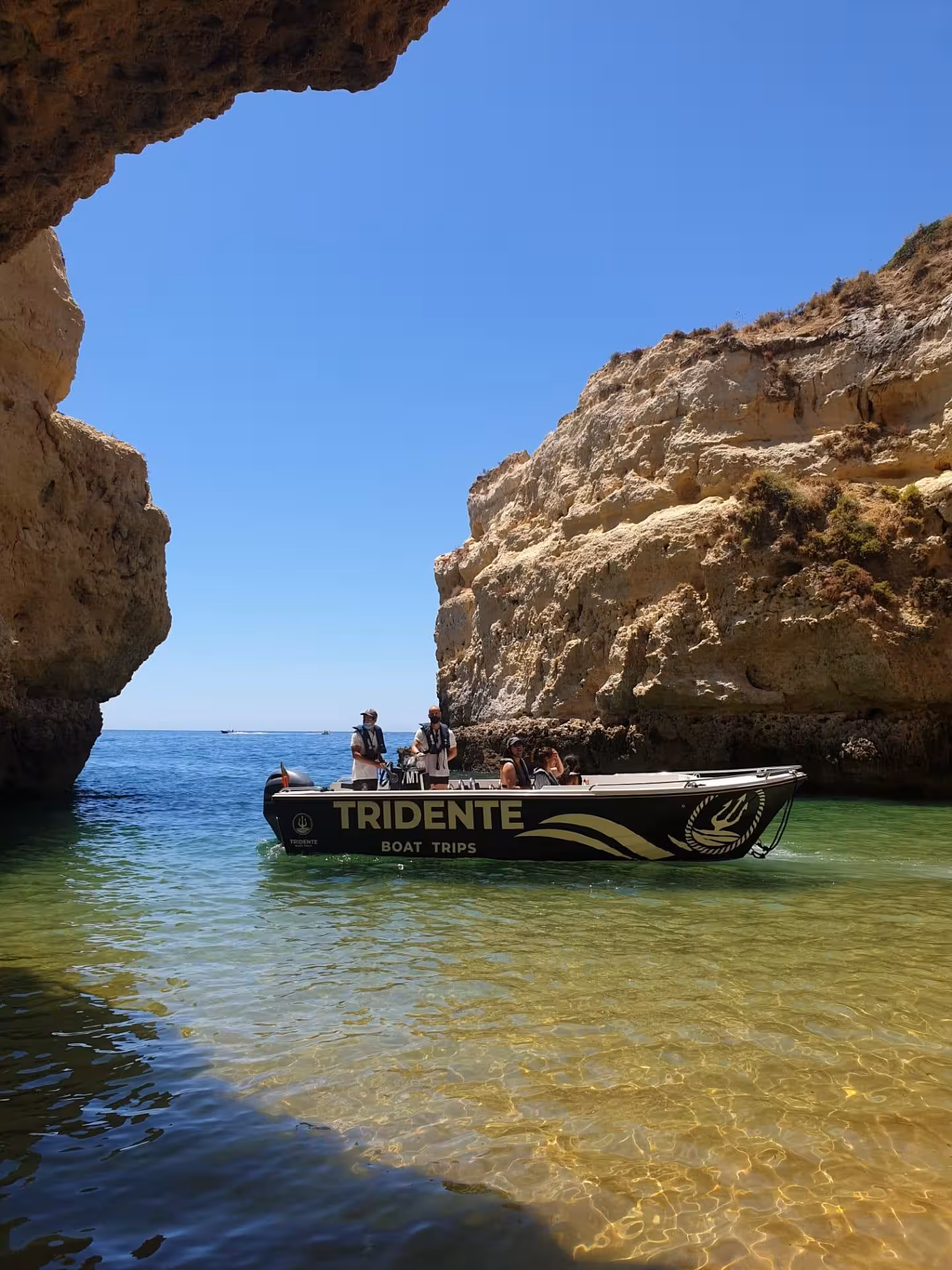 Small group on a Tridente boat entering Benagil Cave on a private 1-hour Algarve tour over crystal-clear water