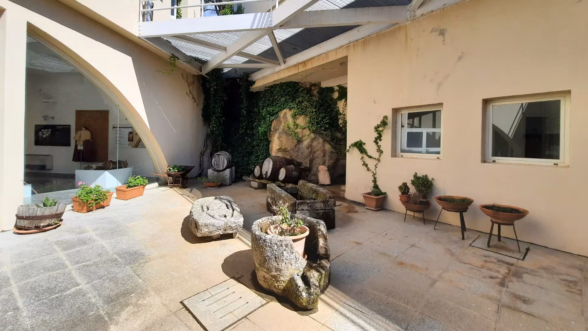 Courtyard of Berchidda Wine Museum with rustic barrels and lush greenery showcasing Sardinian heritage.