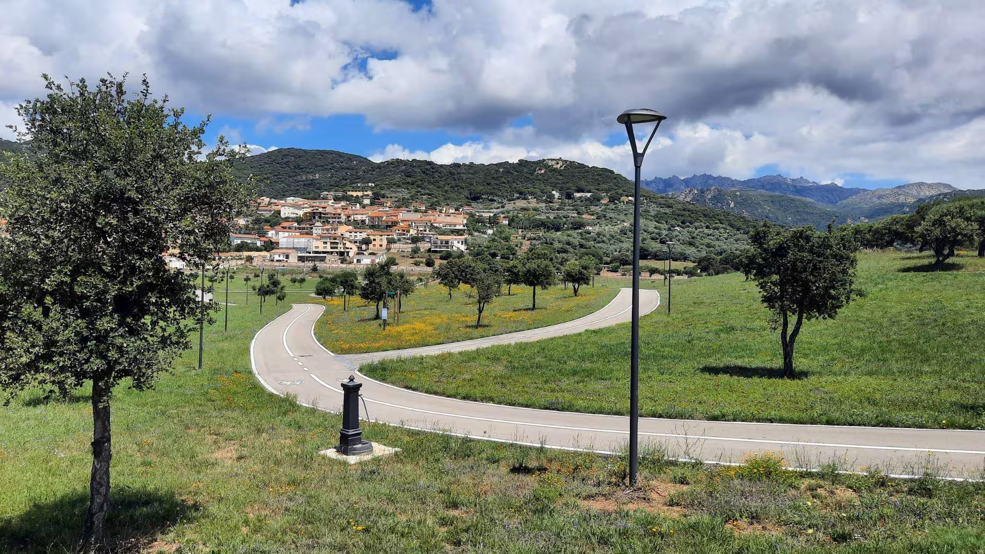 Scenic view of Berchidda with winding road, lush greenery, and mountains perfect for a wine tasting tour.