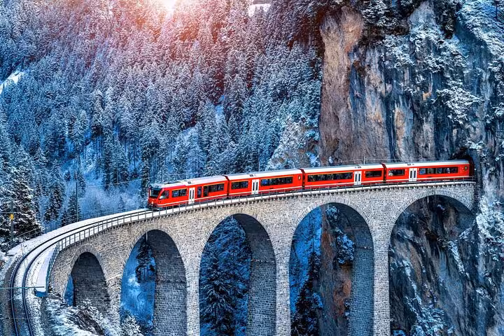 Bernina Express crossing the Landwasser Viaduct in winter, iconic Swiss Alps rail journey to St. Moritz