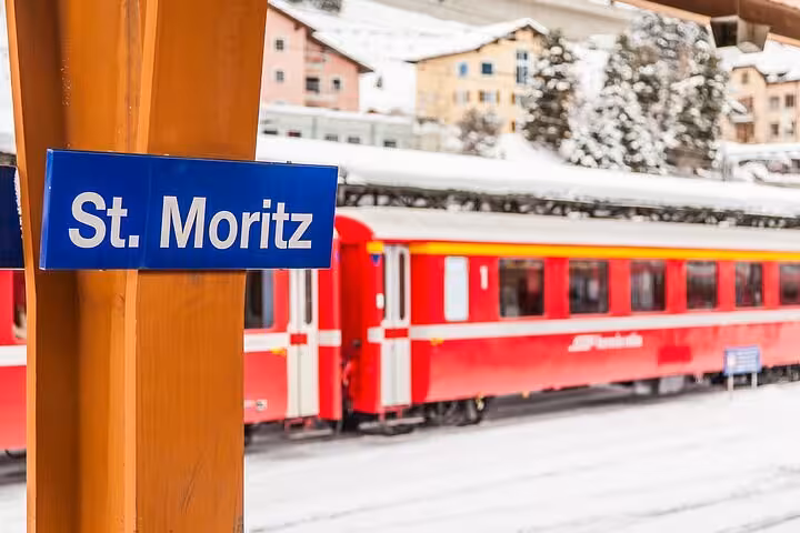 St. Moritz station sign with red Bernina Express train in snowy Alps on St. Moritz day tour