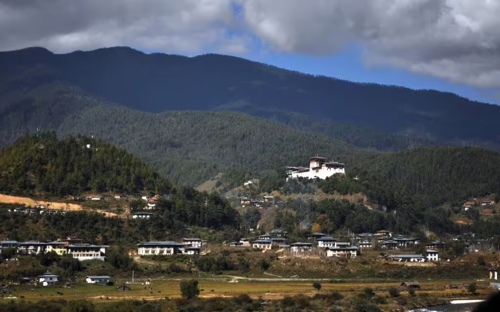 Panoramic view of Bhutan's lush green hills and traditional architecture on a 12-day guided tour.