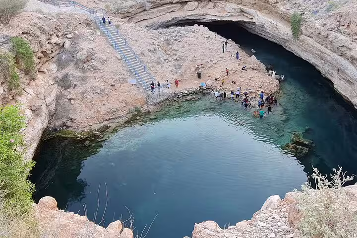 Tourists explore the stunning Bimmah Sinkhole with its turquoise waters and natural rock formations in Oman.