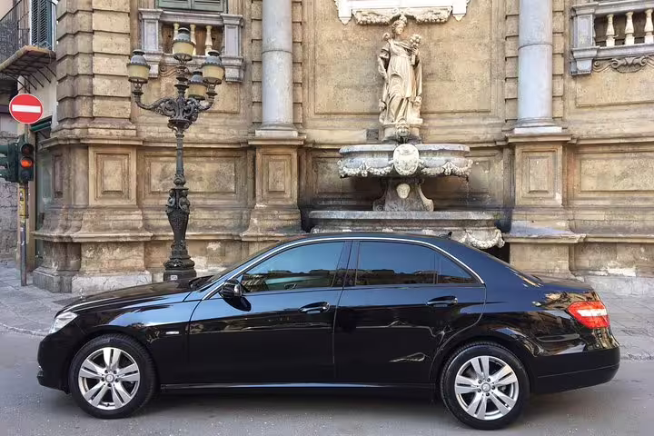 Black luxury sedan used for private Palermo Airport transfer parked near historic city landmark close to Hotel Garibaldi